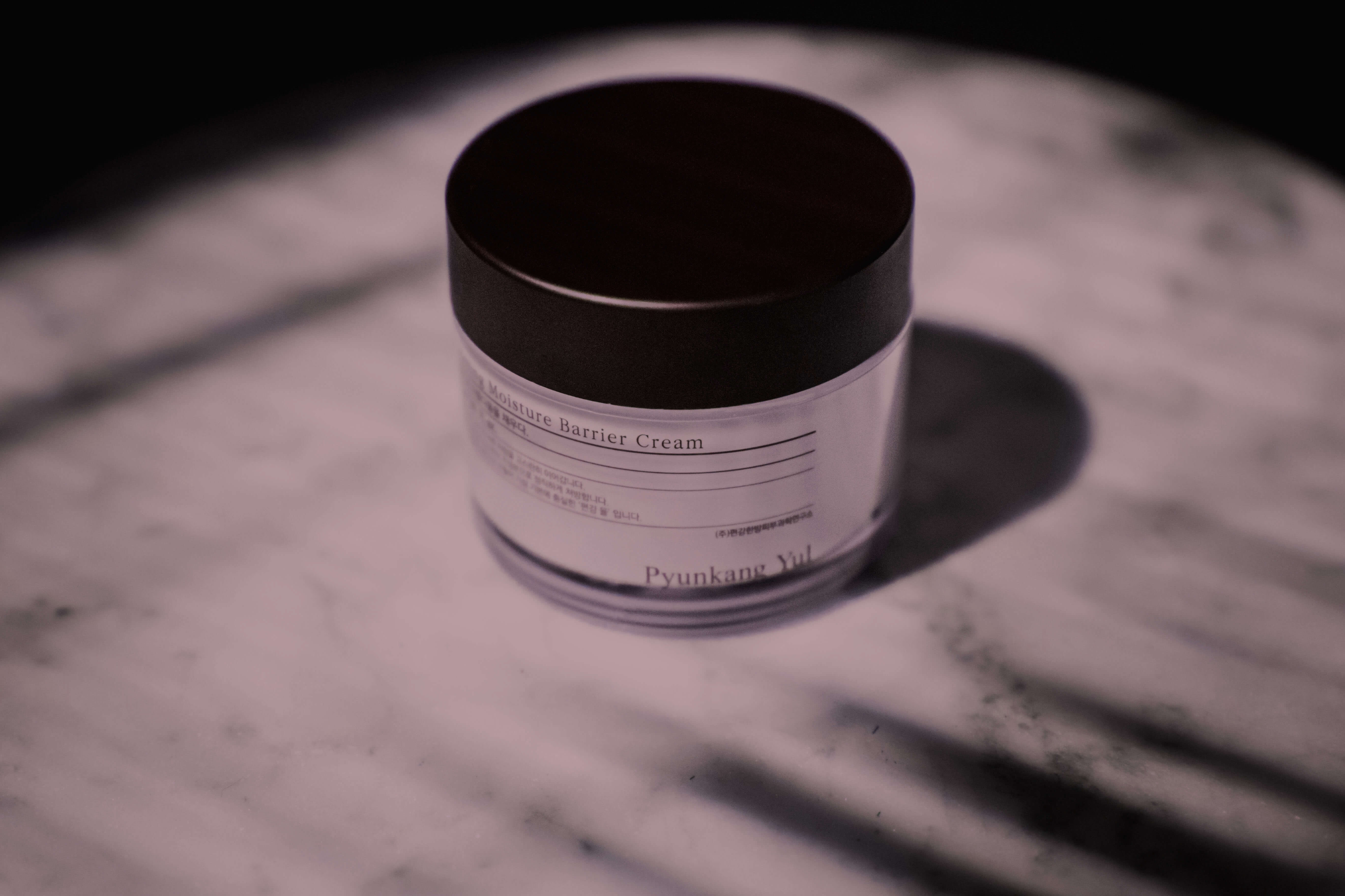 Monochromatic image of a jar of cream with branding on it.